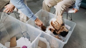 Segregacja odpadów w firmie – pracownicy przy pojemnikach na śmieci